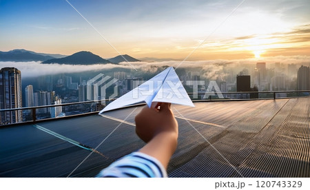 A paper airplane glides against the skyline at sunset, showcasing a panoramic view of the city shrouded in morning fog. Generative AI 120743329