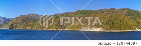 青空バックに見るカラフルな紅葉に囲まれた御母衣湖のパノラマ情景 120744897