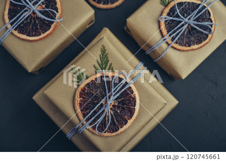 Gifts boxes in golden paper with dry oranges Gifts boxes in golden paper with dry oranges 120745661