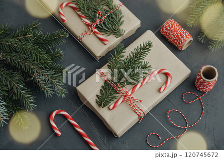Gift boxes in craft paper with candy canes and coniferous tree 120745672