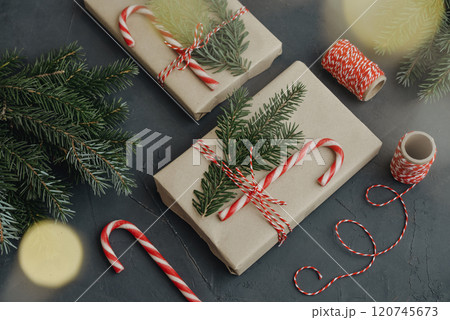 Gift boxes in craft paper with candy canes and coniferous tree 120745673