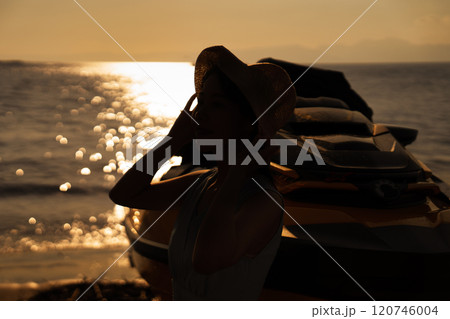 海の夕日と女性のシルエット 120746004