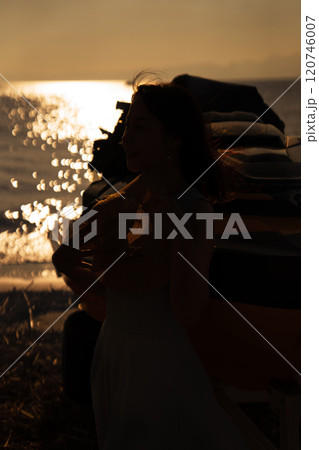 海の夕日と女性のシルエット 120746007