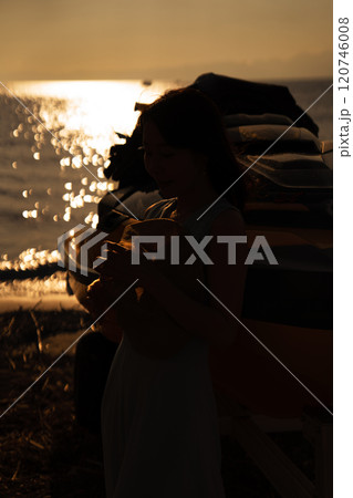 海の夕日と女性のシルエット 120746008
