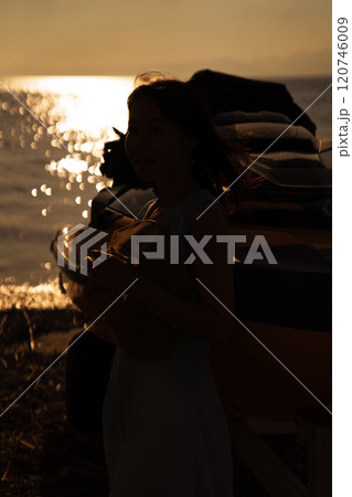 海の夕日と女性のシルエット 120746009