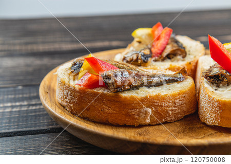 fish sandwich with butter and sprats, lemon on a wooden plate, close up 120750008