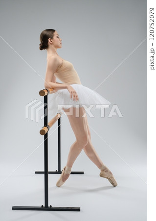 Ballet dancer practicing en pointe at the barre in a studio setting 120752079