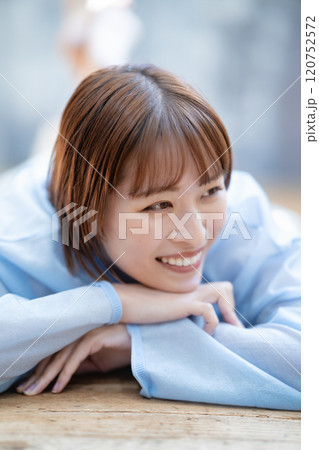 フローリングに寝転ぶショートボブの若い女性 120752572