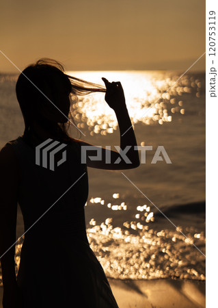 海の夕日と女性のシルエット 120753119