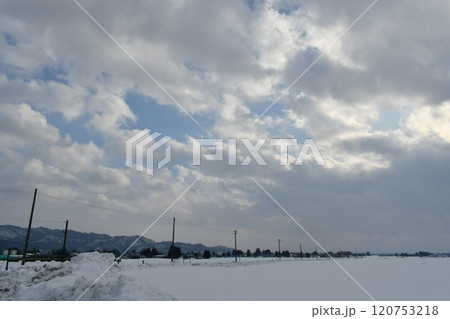 分厚い雲と合間から見える青い空の下の雪が積もった長井市の町外れの風景 分厚い雲と合間から見える青い空の下の雪が積もった長井市の町外れの風景 120753218