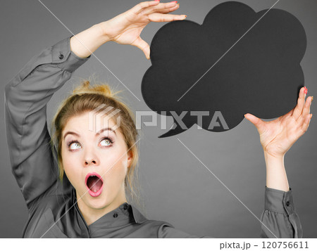 Shocked woman holding black thinking bubble Shocked woman holding black thinking bubble 120756611