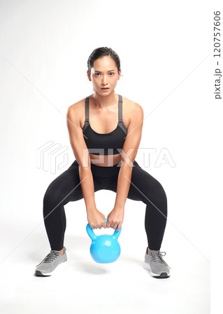 an asian woman is working out with kettlebell wearing the sport exercise suit with white background, 120757606