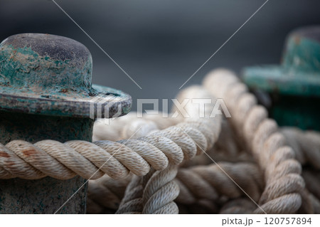 Nautical beauty of weathered bollards and coiled rope at the harbor edge during twilight hours Nautical beauty of weathered bollards and coiled rope at the harbor edge during twilight hours 120757894