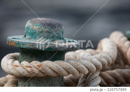 Maritime details captured in a close-up of weathered dock post and rope intertwined along the shore Maritime details captured in a close-up of weathered dock post and rope intertwined along the shore 120757895