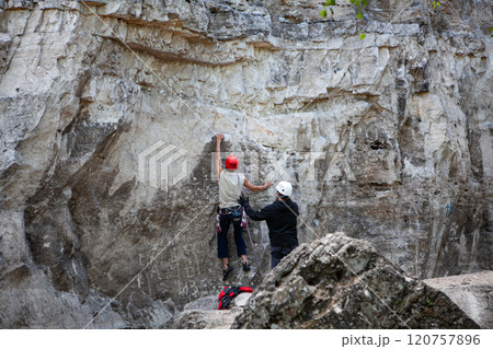 Climber prepares for ascent while belayer ensures safety in stunning rocky landscape 120757896