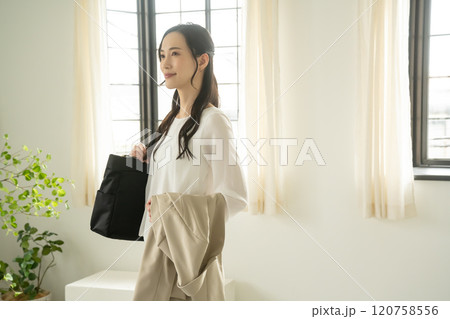 屋内でショルダーバッグとジャケットを持つ女性 120758556