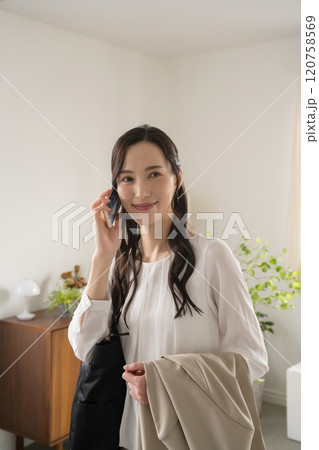 屋内で出かける準備をして電話をする女性 120758569