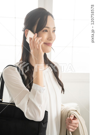 屋内で出かける準備をして電話をする女性 120758578