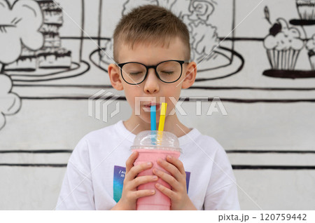 A boy drinks a milkshake cocktail through straws 120759442