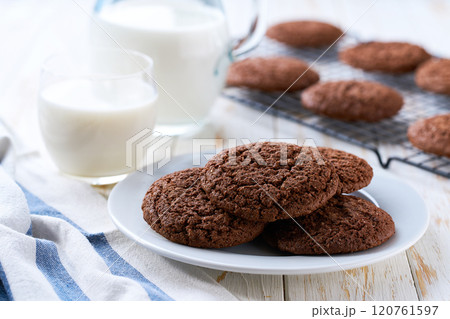 Tasty chocolate cookies and a jug of fresh milk on a light kitchen table, healthy breakfast. 120761597