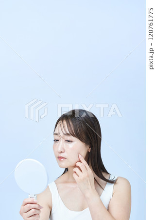 疲れた表情でスキンケアをするミドル世代の女性 120761775