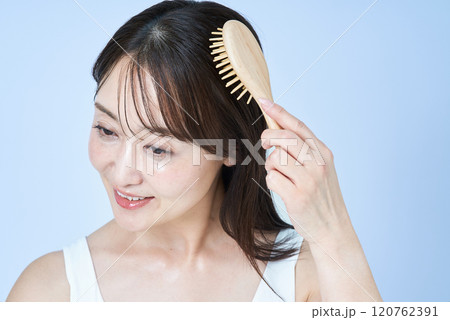 ブラシで髪をブラッシングするミドル世代の女性 120762391