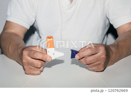 Man holding asthma inhaler in his hands. 120762669