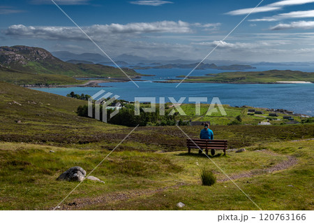 Single Woman On Bench Looks Over Atlantic Coast With Summer Isles, Isle Ristol And Eilean Mullagrach Near Village Altandhu In The Highlands Of Scotland, UK 120763166