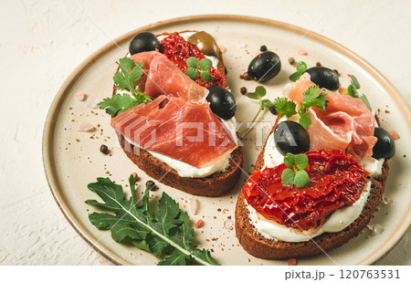 sandwiches with cheese and prosciutto, dried tomatoes and olives, breakfast on a plate, sandwiches with cheese and prosciutto, dried tomatoes and olives, breakfast on a plate, 120763531