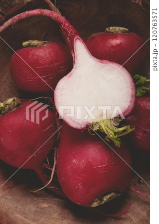 Freshly harvested radishes displayed in a rustic wooden bowl showcasing their vibrant color and texture Freshly harvested radishes displayed in a rustic wooden bowl showcasing their vibrant color and texture 120763571