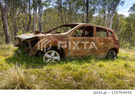 An abandoned and burnt out car in a remote area 120764048