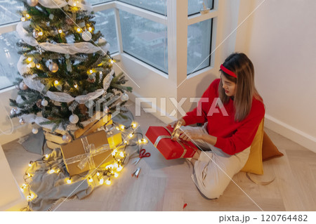 Red sweater woman packing red box for decorating her Christmas tree in the apartment. 120764482