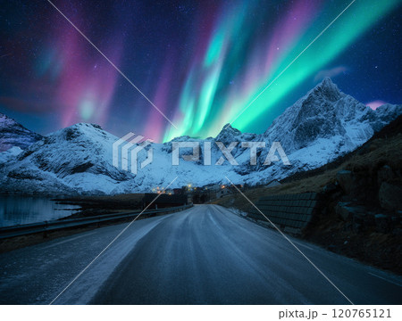 Northern lights over road, snowy mountains, village at night 120765121