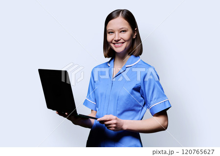 Female nurse with laptop, looking at camera on white studio background Female nurse with laptop, looking at camera on white studio background 120765627