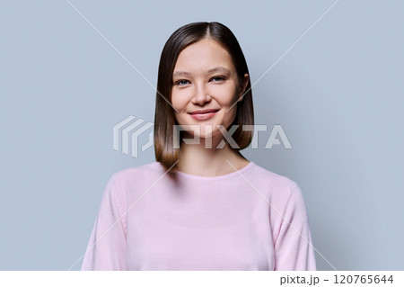 Headshot portrait of young smiling attractive woman on grey background 120765644