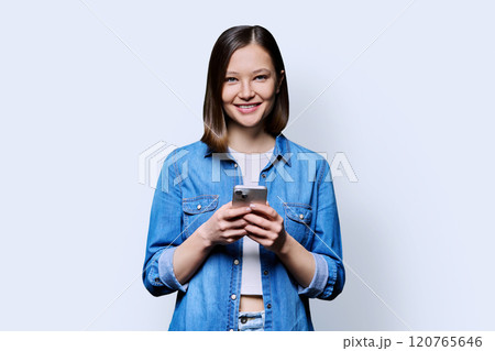 Young smiling woman using smartphone looking at camera in white background 120765646