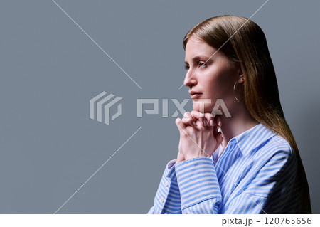 Profile view, young serious female looking forward on gray studio background 120765656