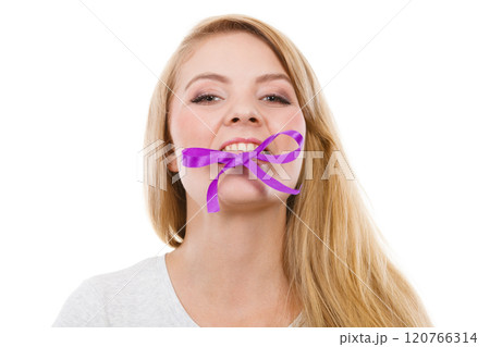 Blonde woman biting decorative purple bow 120766314