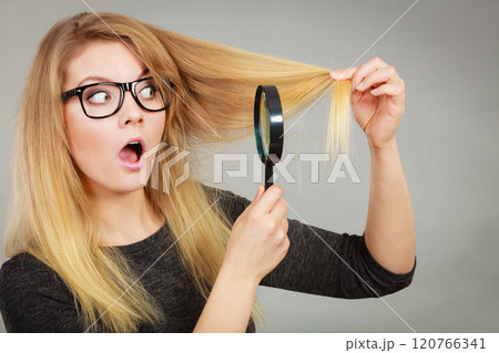 Woman holding magnifying glass looking at hair 120766341