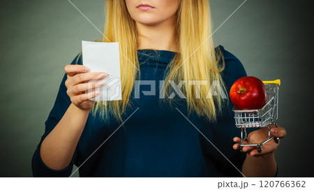 Worried woman holding shopping basket with fruits 120766362