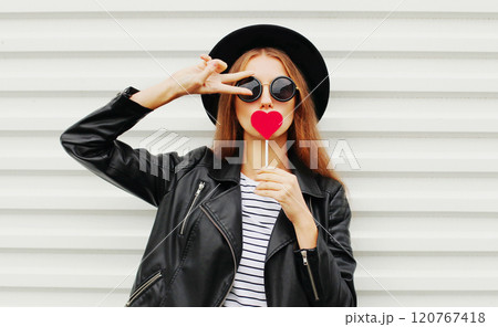 Cool young girl with red lollipop heart wearing fashion black hat leather jacket on white background Cool young girl with red lollipop heart wearing fashion black hat leather jacket on white background 120767418