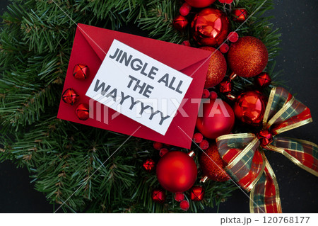 Christmas handmade wreath made of festive decorations with red envelope and paper note with JINGLE ALL THE WAY text. Winter holiday celebration greeting card 120768177