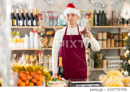 Guy seller raises glass of champagne in grocery store 120770700