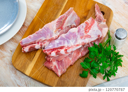 Fresh raw pork ribs on kitchen board with parsley, meat with bone. Cooking delicious food or grilling 120770787