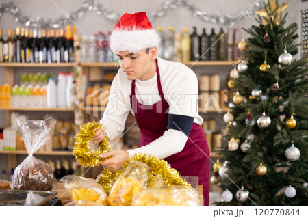 Young salesman decorates grocery store for christmas 120770844
