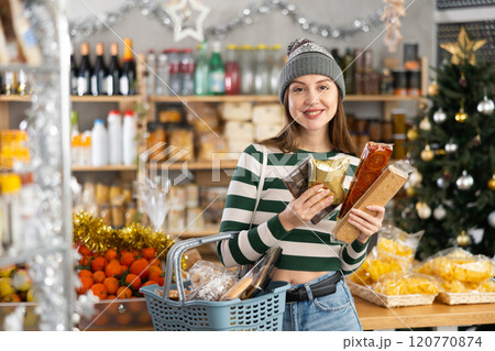 While shopping on eve of New Year holidays, young lady buys sweets for festive party 120770874