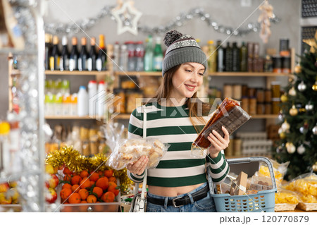 While shopping on eve of New Year holidays, young lady buys sweets for festive party 120770879