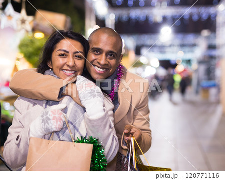 Happy married couple with packages of gifts at new year fair Happy married couple with packages of gifts at new year fair 120771116