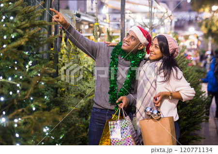 Family couple choosing christmas tree at christmas fair 120771134