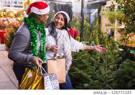 Positive woman and man buying Christmas tree and toys at Christmas Fair 120771185